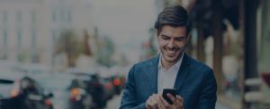 Smiling business man on street looking at smartphone