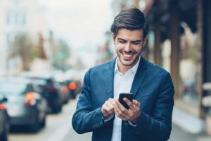 Smiling business man on street looking at smartphone